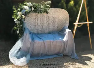 Wicker chair with drape and floral wreath for a wedding.